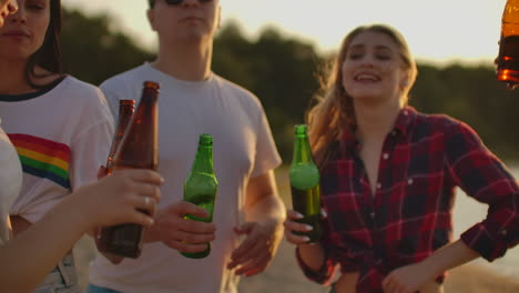 Group-of-young-people-celebrate-the-end-of-the-semester-with-beer.-They-clink-and-drink-beer-on-the-open-air-party.